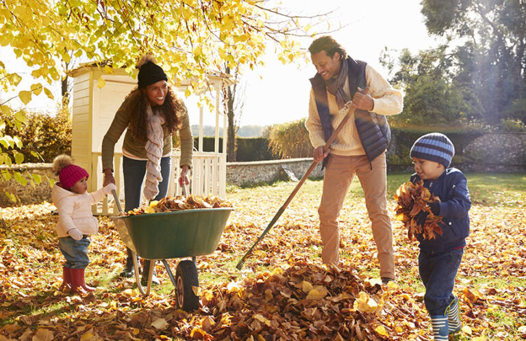 family raking leaves in their yard