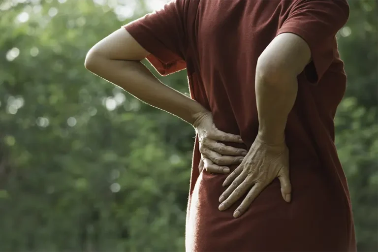 closeup hands of woman touching her back pain in nature background