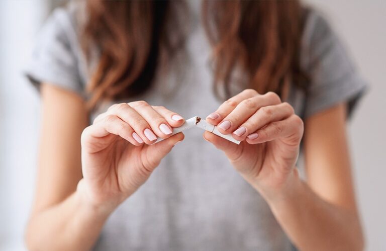 Chest-down of woman breaking a cigarette