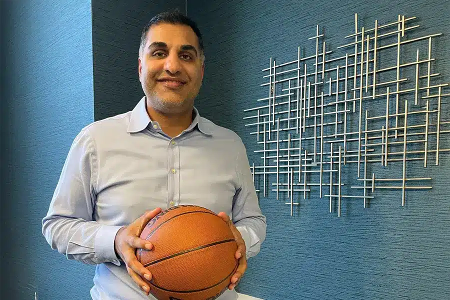 Man holding a basketball with a metal fixture on the wall