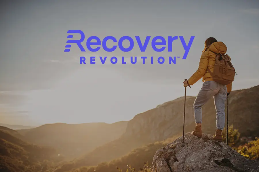 female hiker looking at sunset with recovery revolution logo