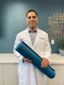Dr. Jazini holding yoga mat