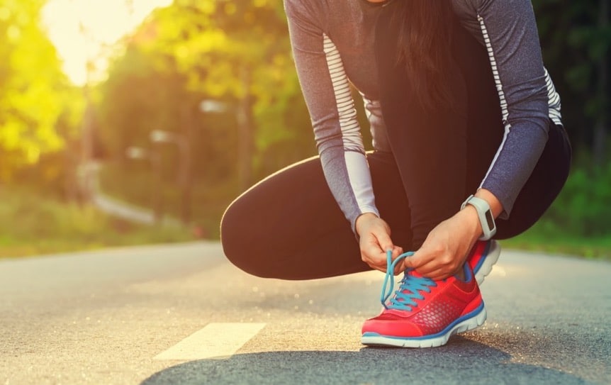 female runner tying her shoes preparing for a jog