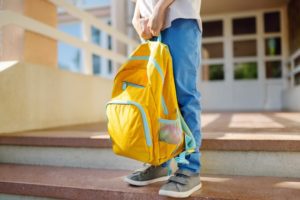 kid holding yellow backpack