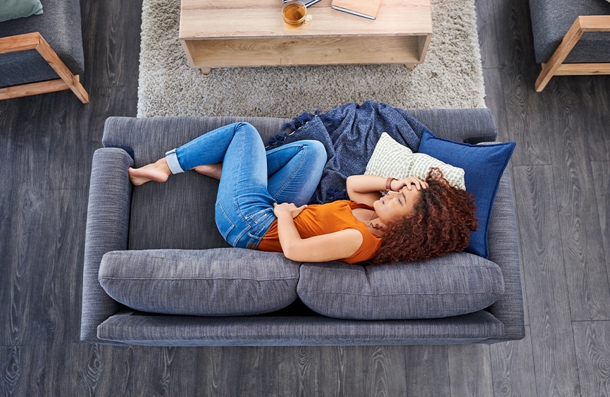 Woman with headache curled up on the couch