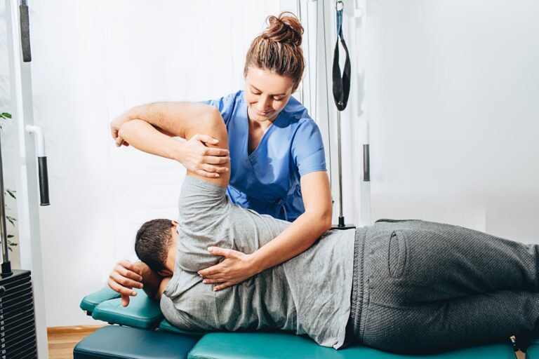 Physical therapist doing manual therapy on man's shoulder