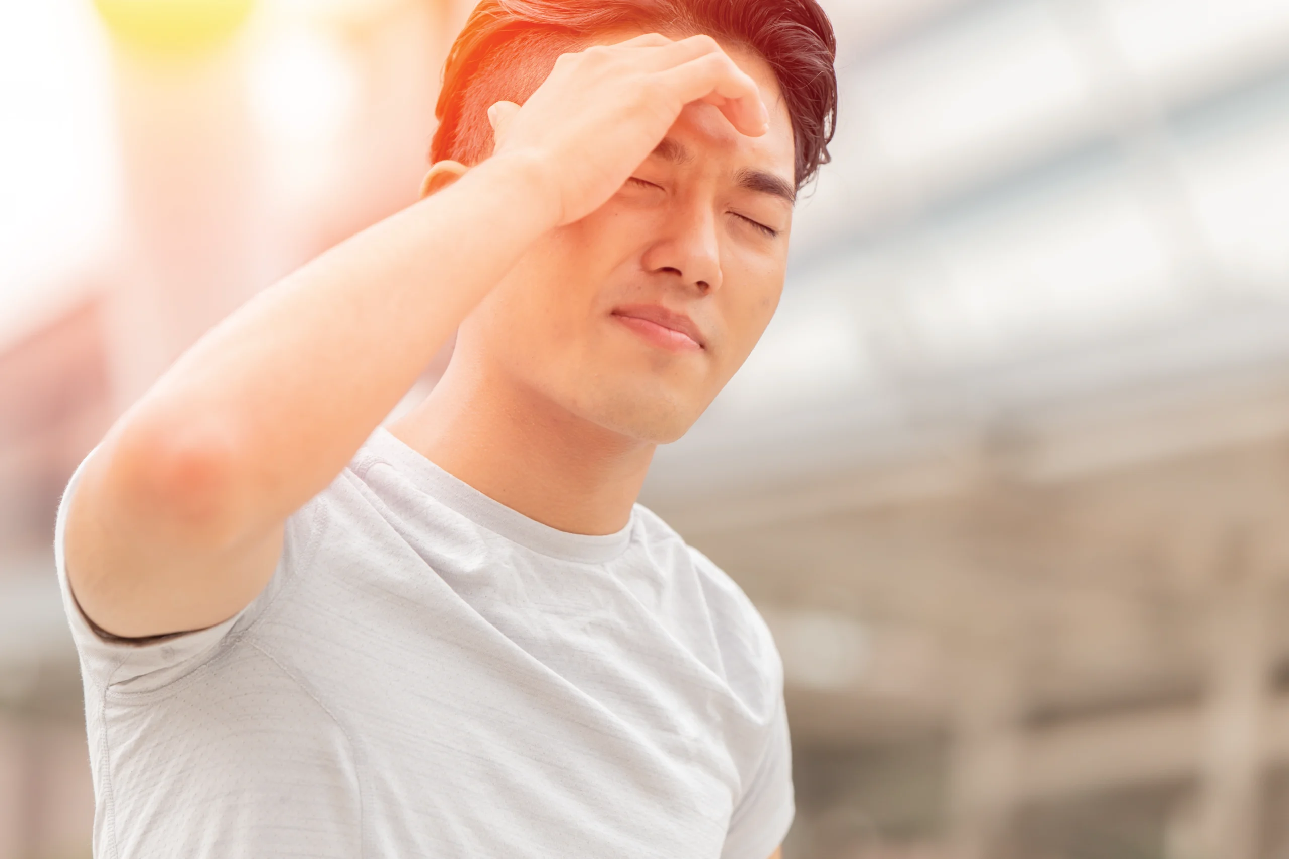 Young male experiencing migraine in summer heat