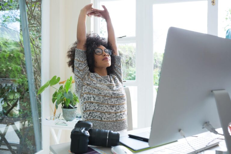 A woman stretching in front of a computer