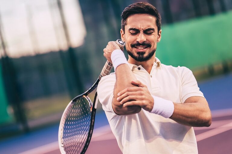 Tennis player gripping his elbow in pain